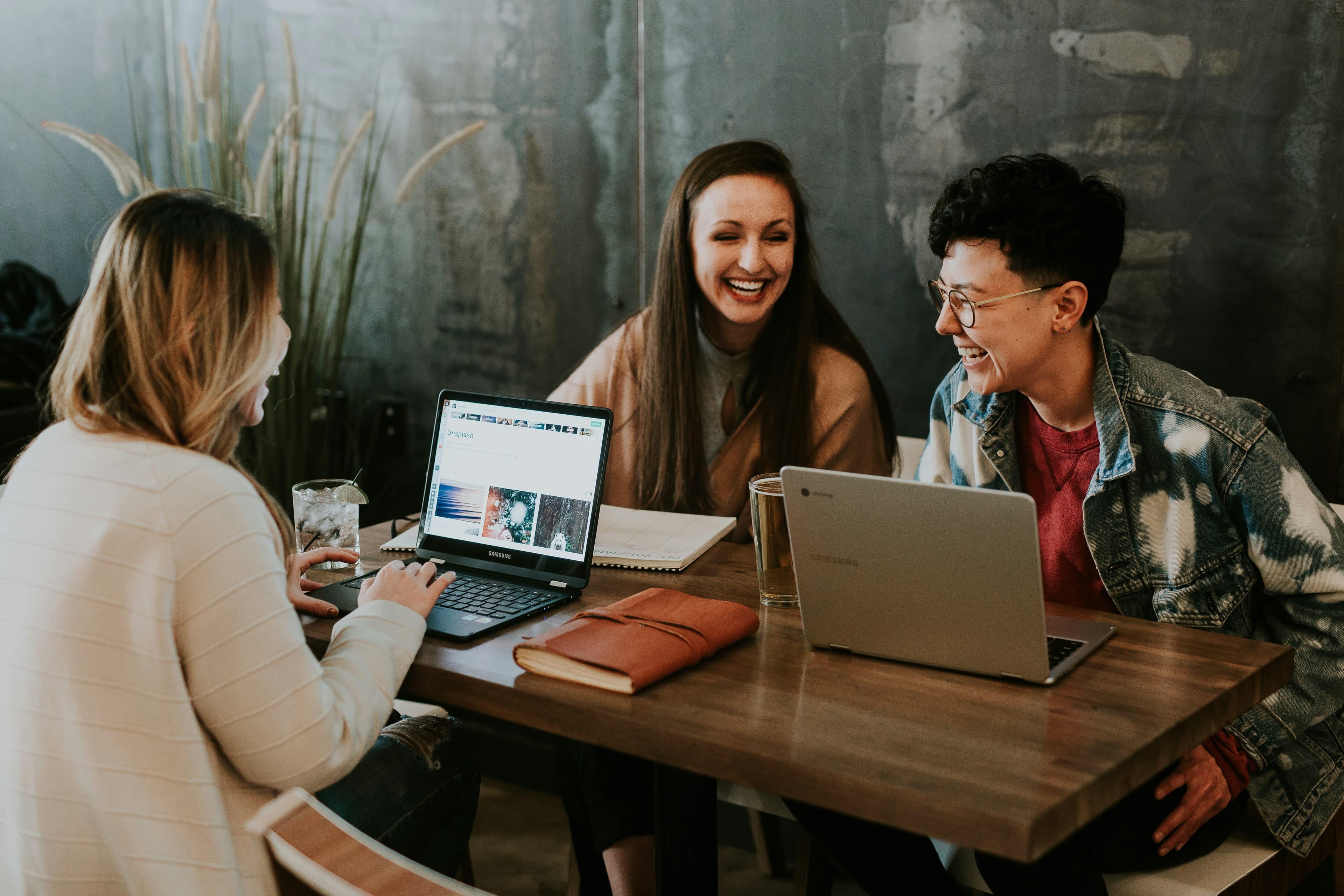 Three people laughing together over their laptops