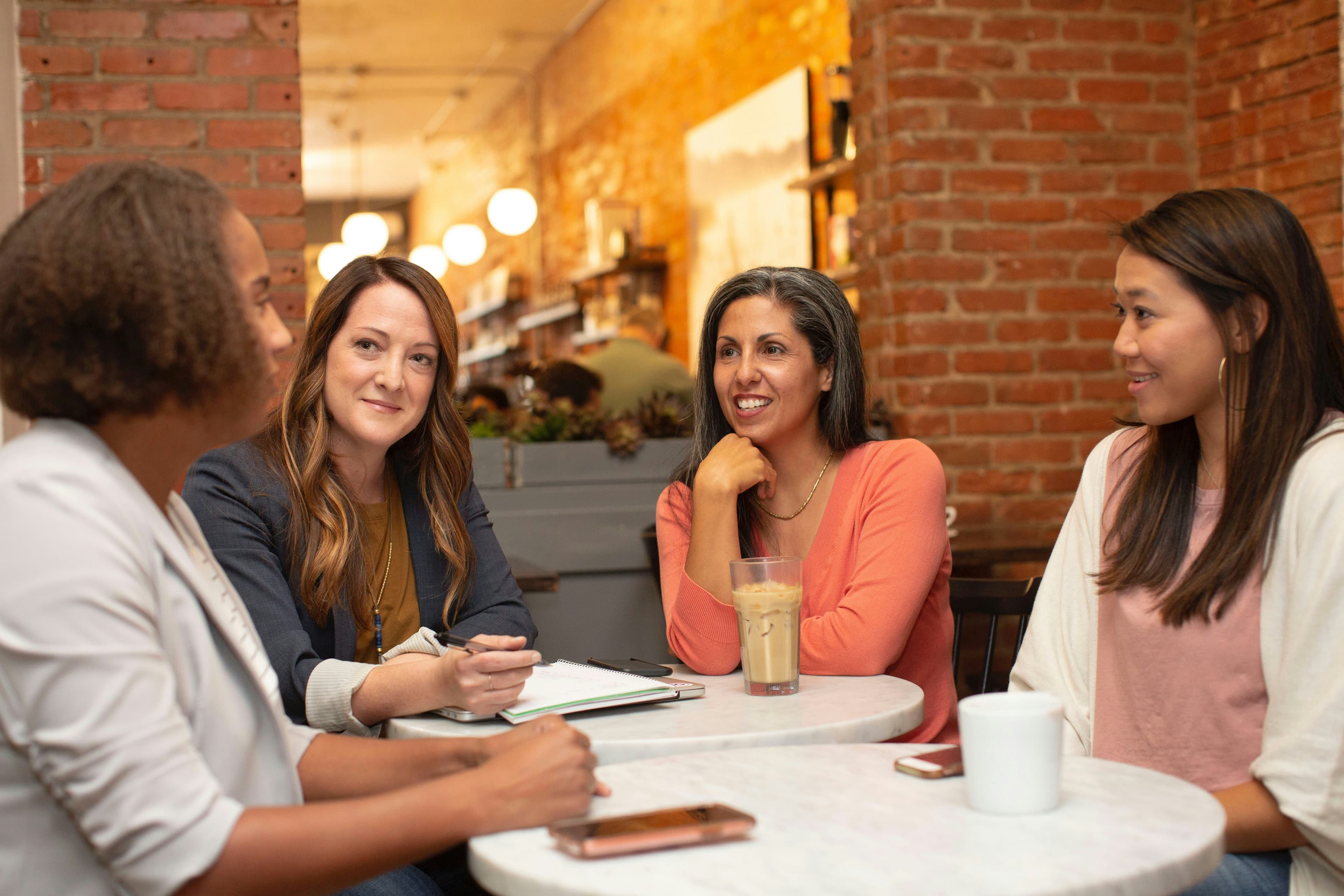 Four women deep in conversation at a café table