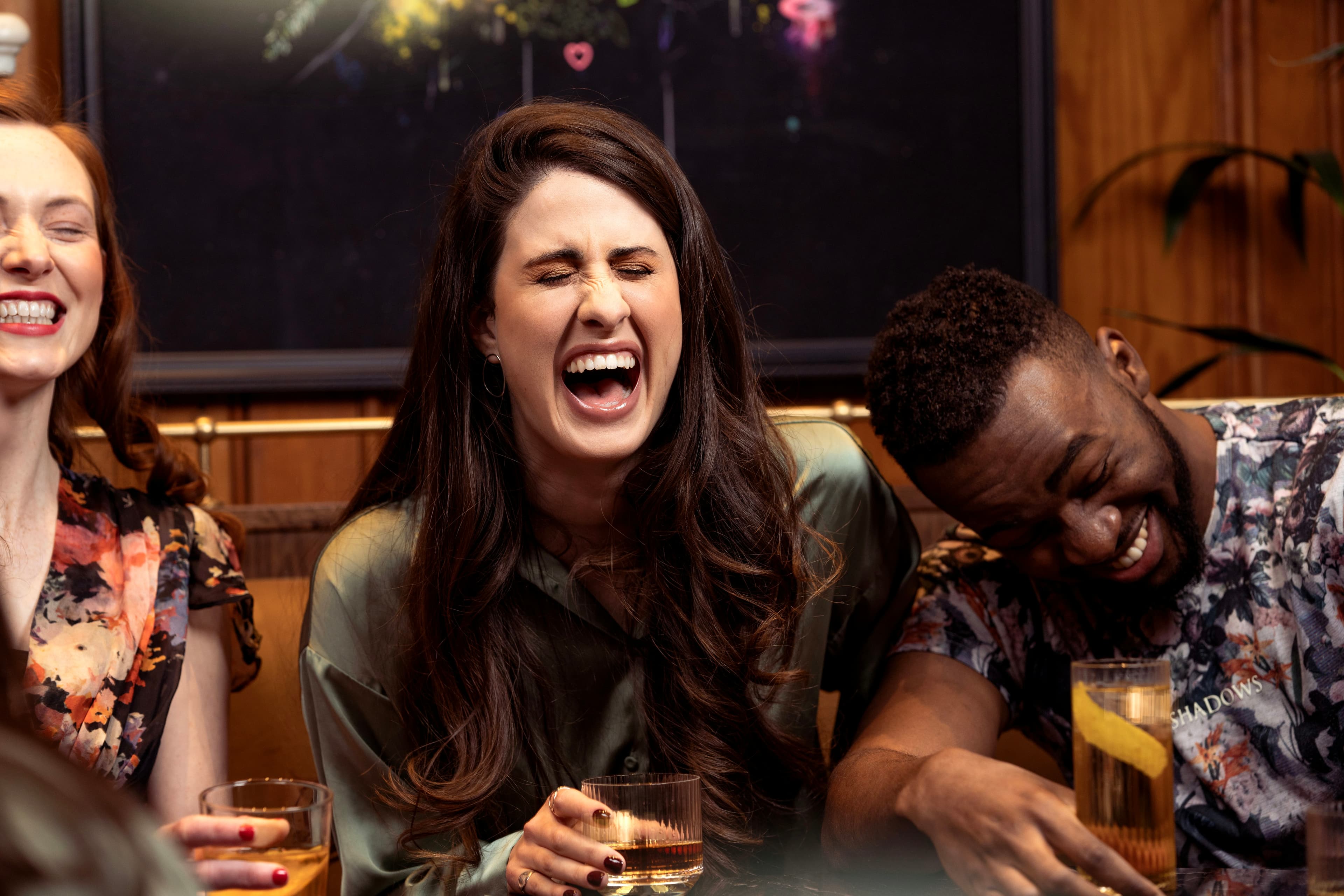 A woman laughing with friends around a table