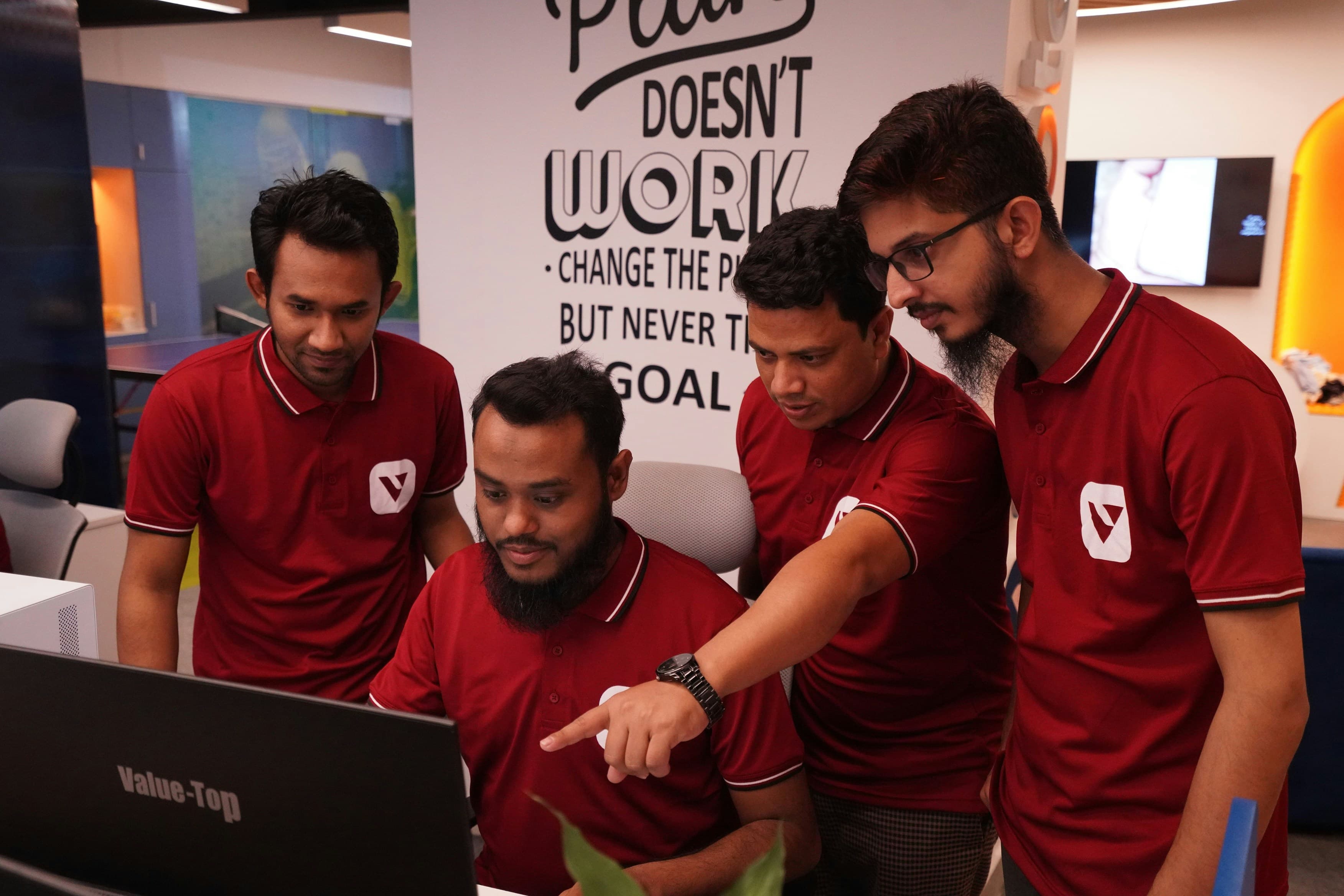 A startup team crowded around a laptop, pointing at the screen